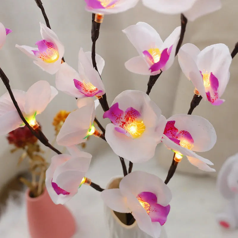 Pink LED orchid branch decorative light on a bedside table.
