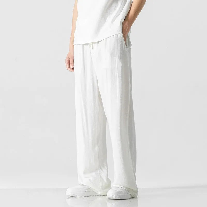Man wearing beige straight-leg cropped linen-style trousers with a drawstring waist.