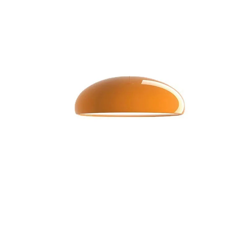 Modern Danish orange iron pendant lamp with adjustable cable over a restaurant dining table.