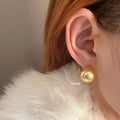 Large pearl stud earrings with geometric silver settings and eight-pointed star motifs