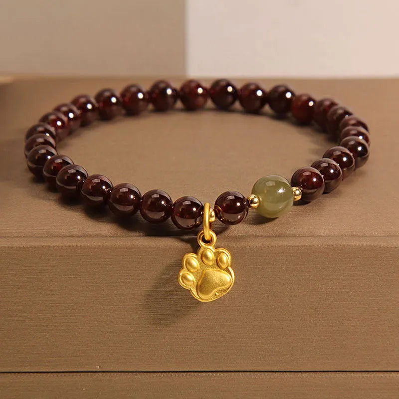 Women's crystal bracelet with a cat's paw garnet design on a polished metal setting.