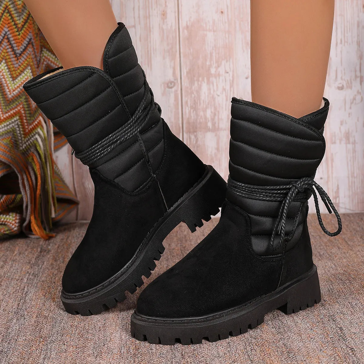 Black women's high-top suede snow boots with chunky rubber sole and lace-up design