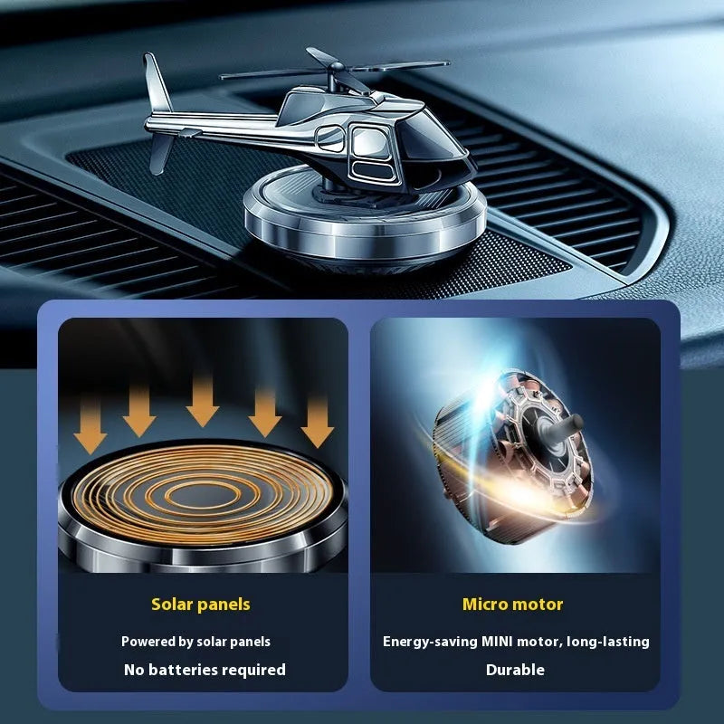 Silver metal solar-powered rotating helicopter car air freshener ornament on a dashboard.
