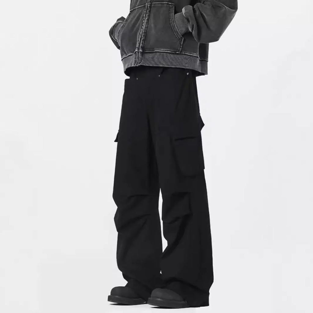 Men's black high-waisted straight-leg trousers with a button fly front, laid flat on a grey background.