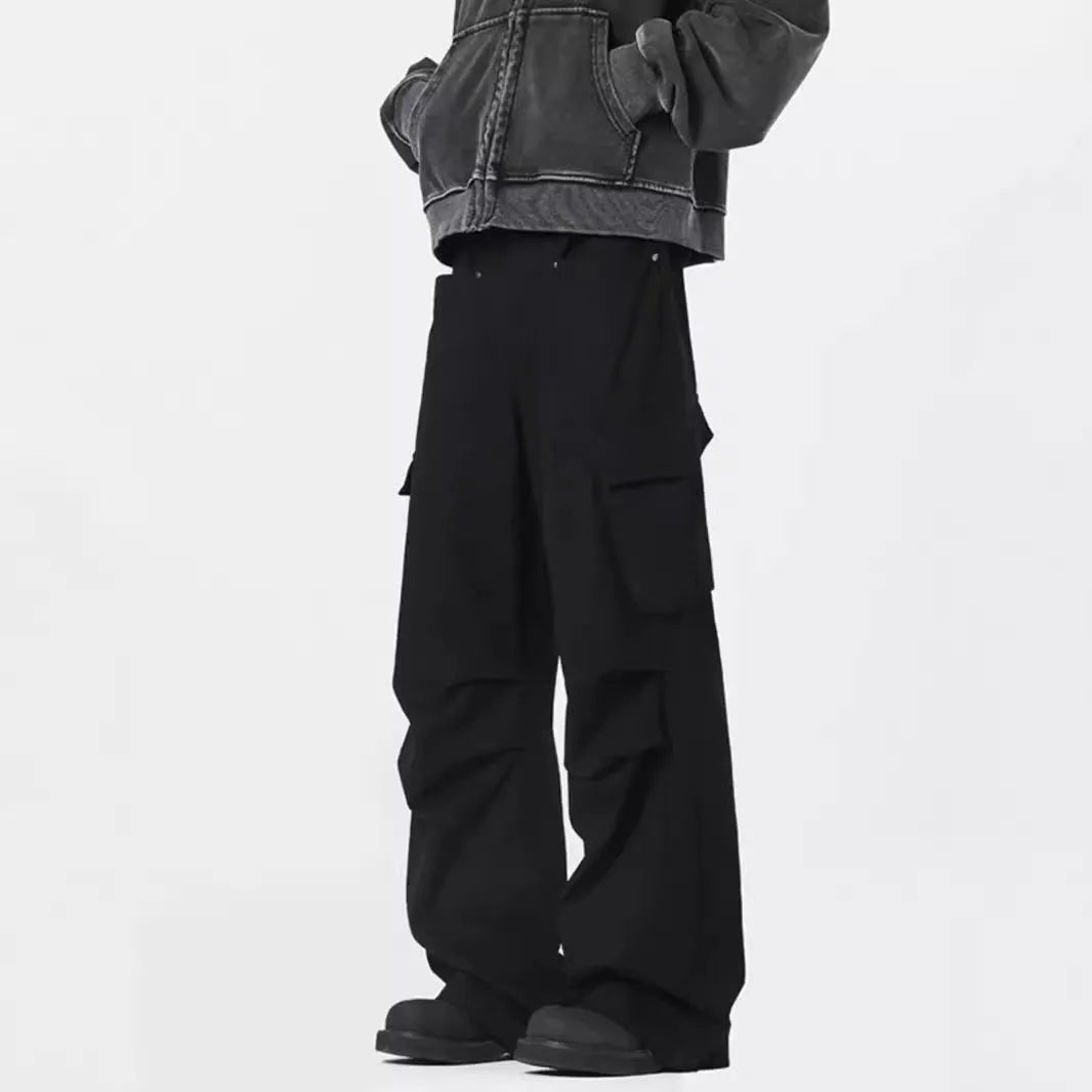 Men's black high-waisted straight-leg trousers with a button fly front, laid flat on a grey background.