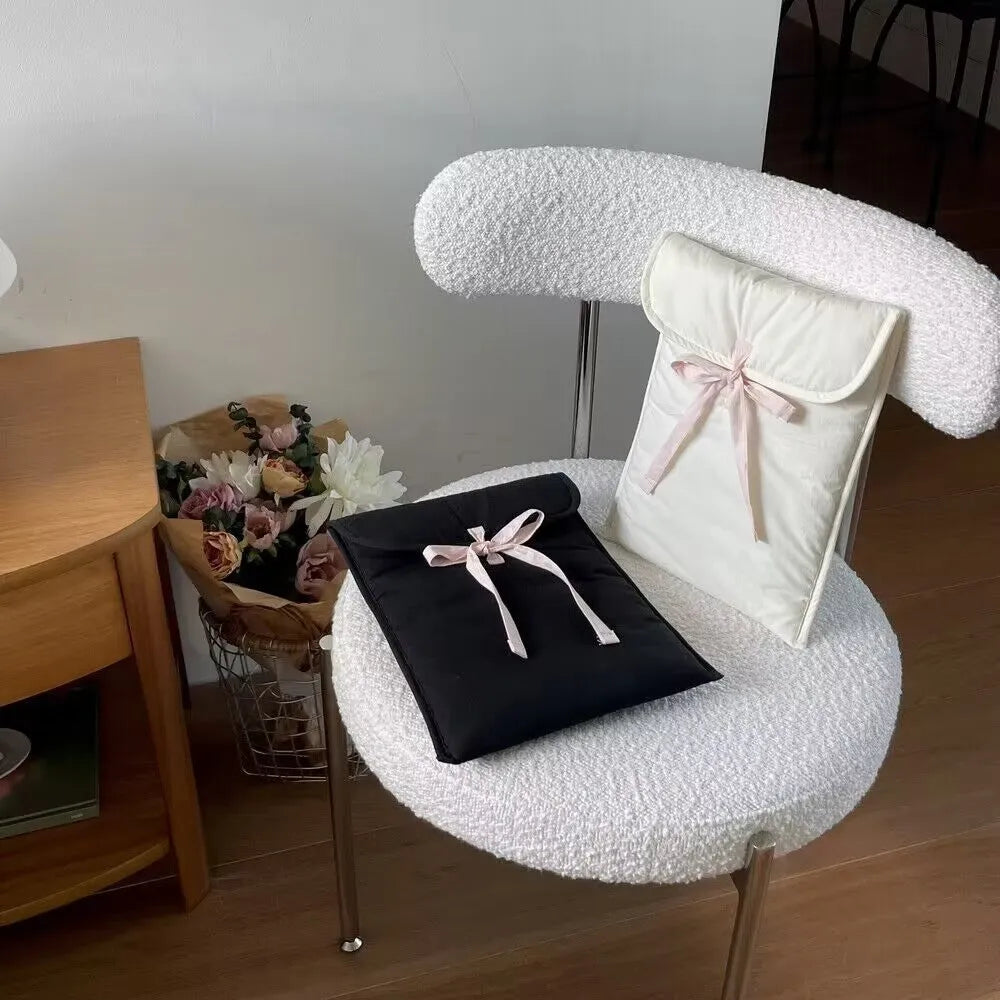 Black and white quilted laptop bag with a large ballet-style bow on the front.