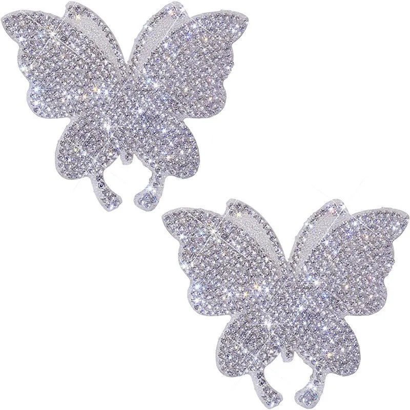 Close-up of a diamond-encrusted glass car sticker in butterfly and bear paw designs on a clear background.