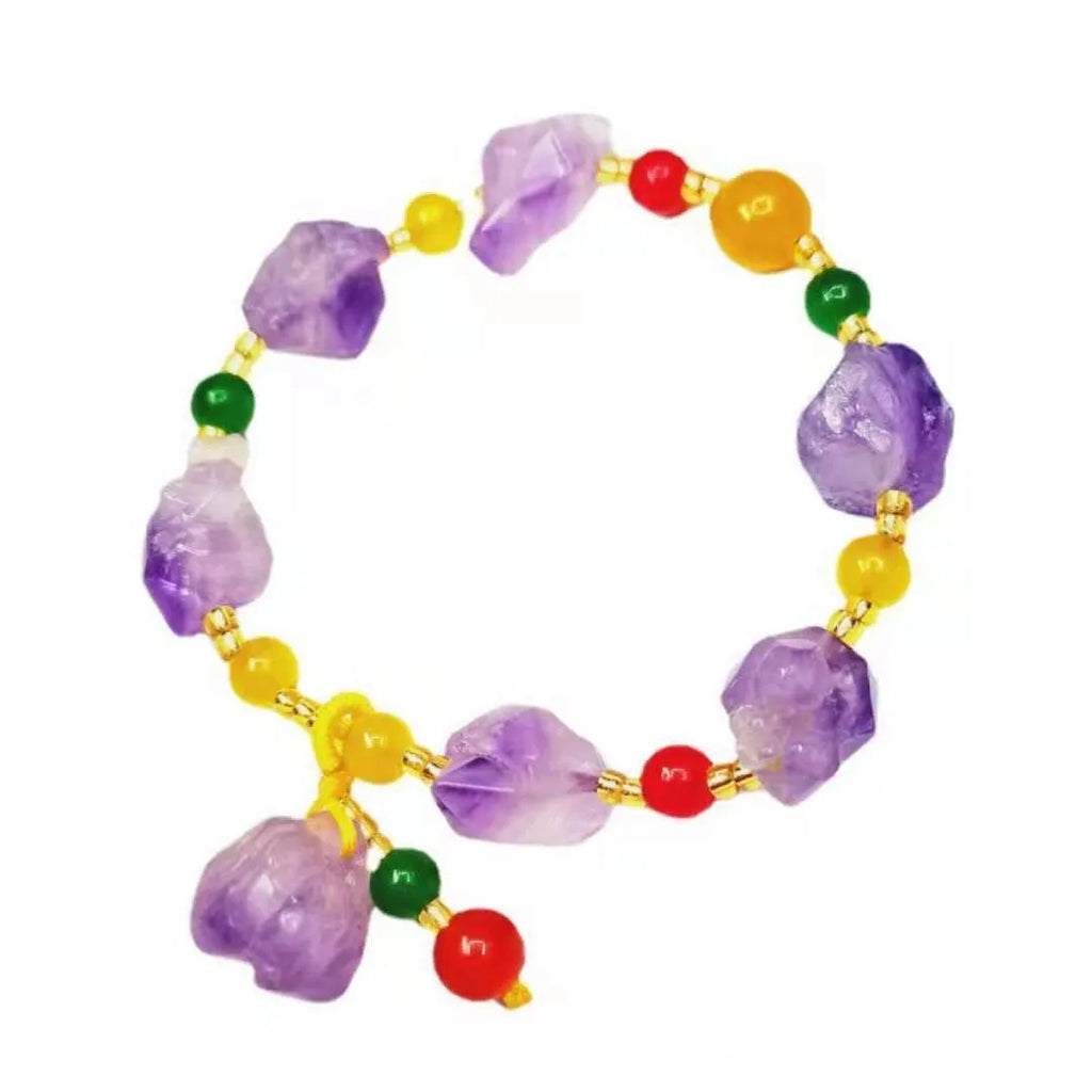 Close-up of a women's bracelet with natural shaped amethyst beads and a silver fu charm on a white background.