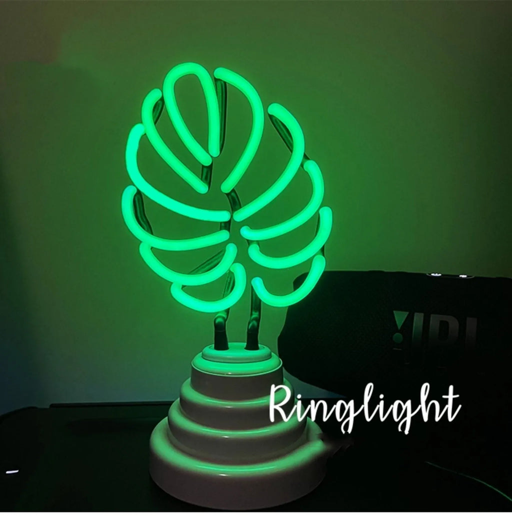 Minimalist white bamboo-shaped desk lamp emitting a soft green light, shown on a table.
