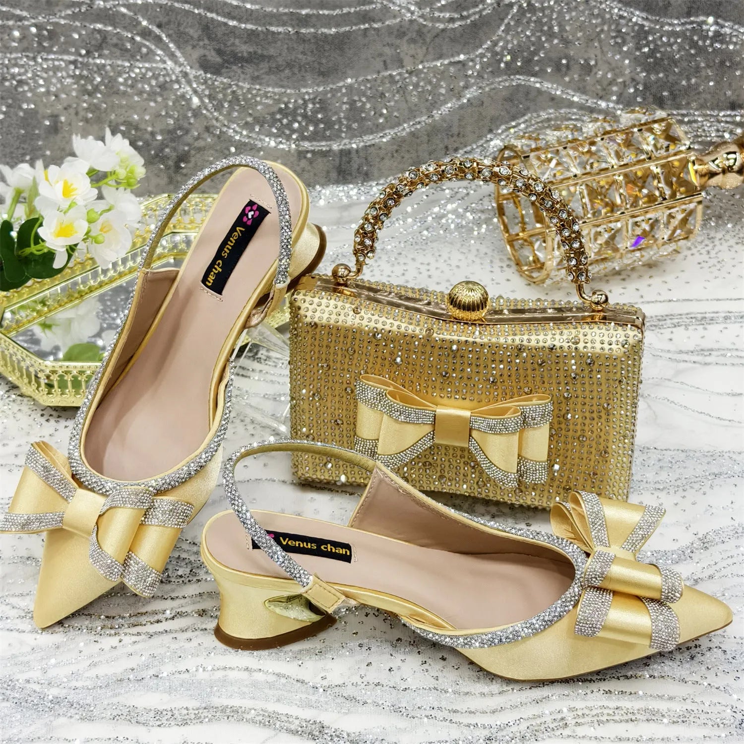 Women's pointed toe sandals with square rhinestone buckle and matching bag on a mid heel.