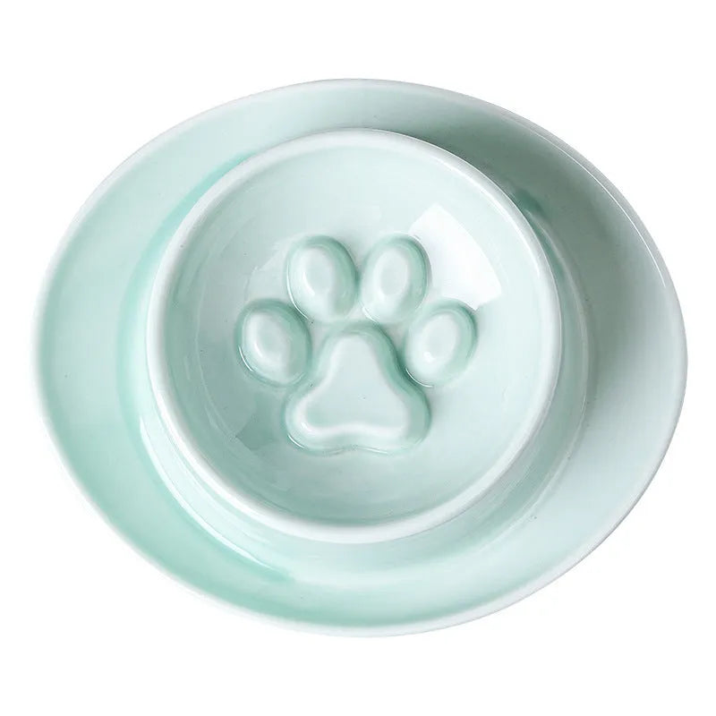 Green ceramic slow feeder pet bowl with internal maze pattern and raised basin design on a wooden floor.