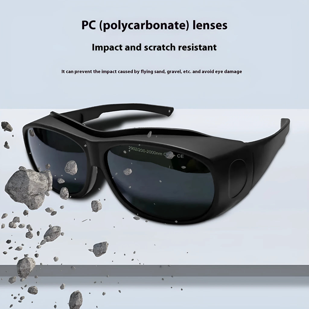 A pair of clear laser and welding safety goggles with a soft cleaning cloth on a dark background.