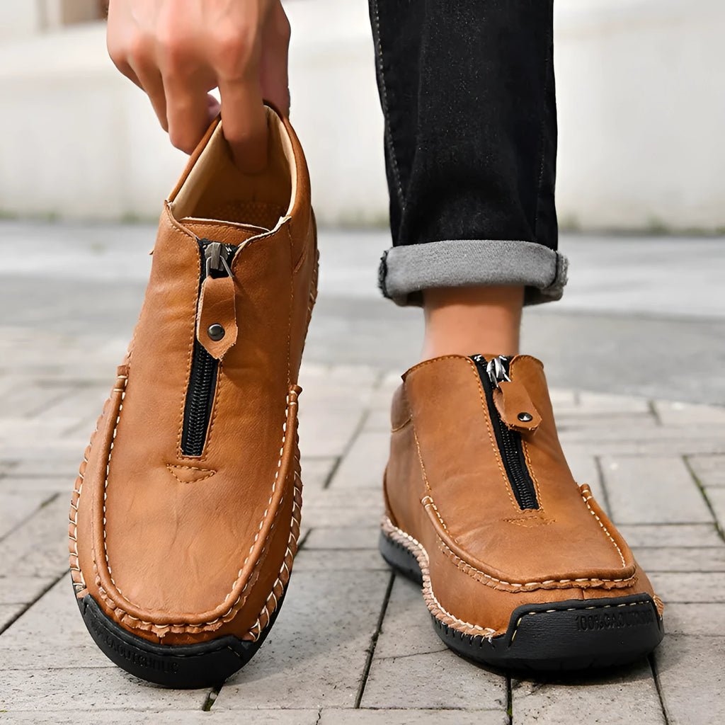 Men's black slip-on leather loafers with round toe and sewn sole detail on a white background.