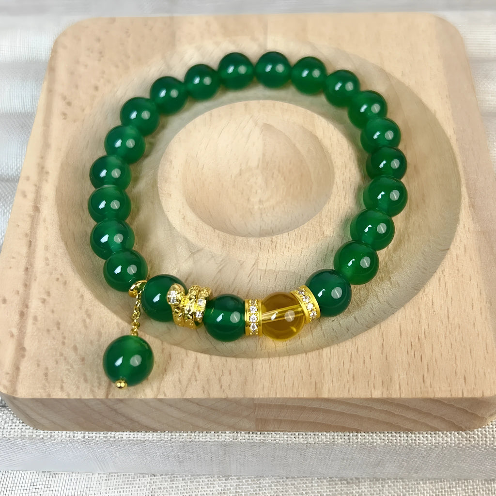 Green and red agate stone bead wealth snake bracelet with copper details on a wrist.