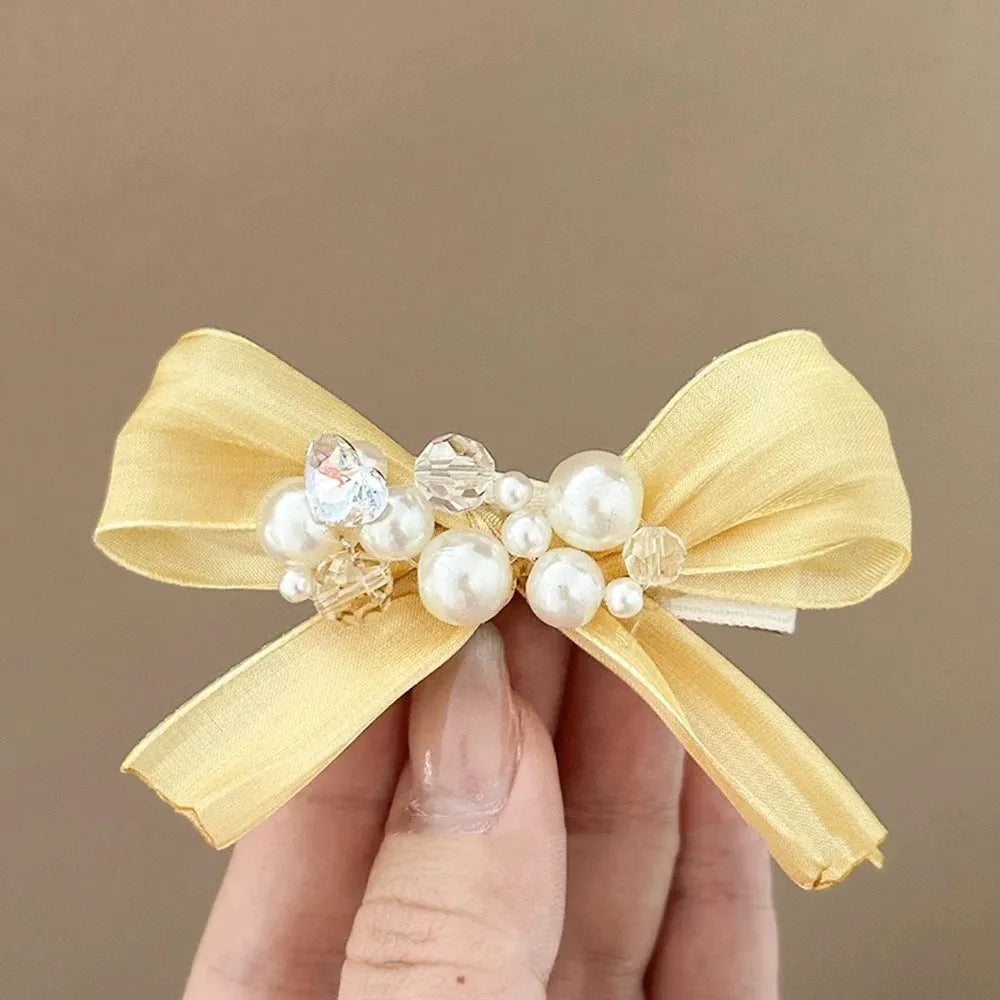 Yellow bow hair clip with rhinestone pearl accents and duckbill clip design