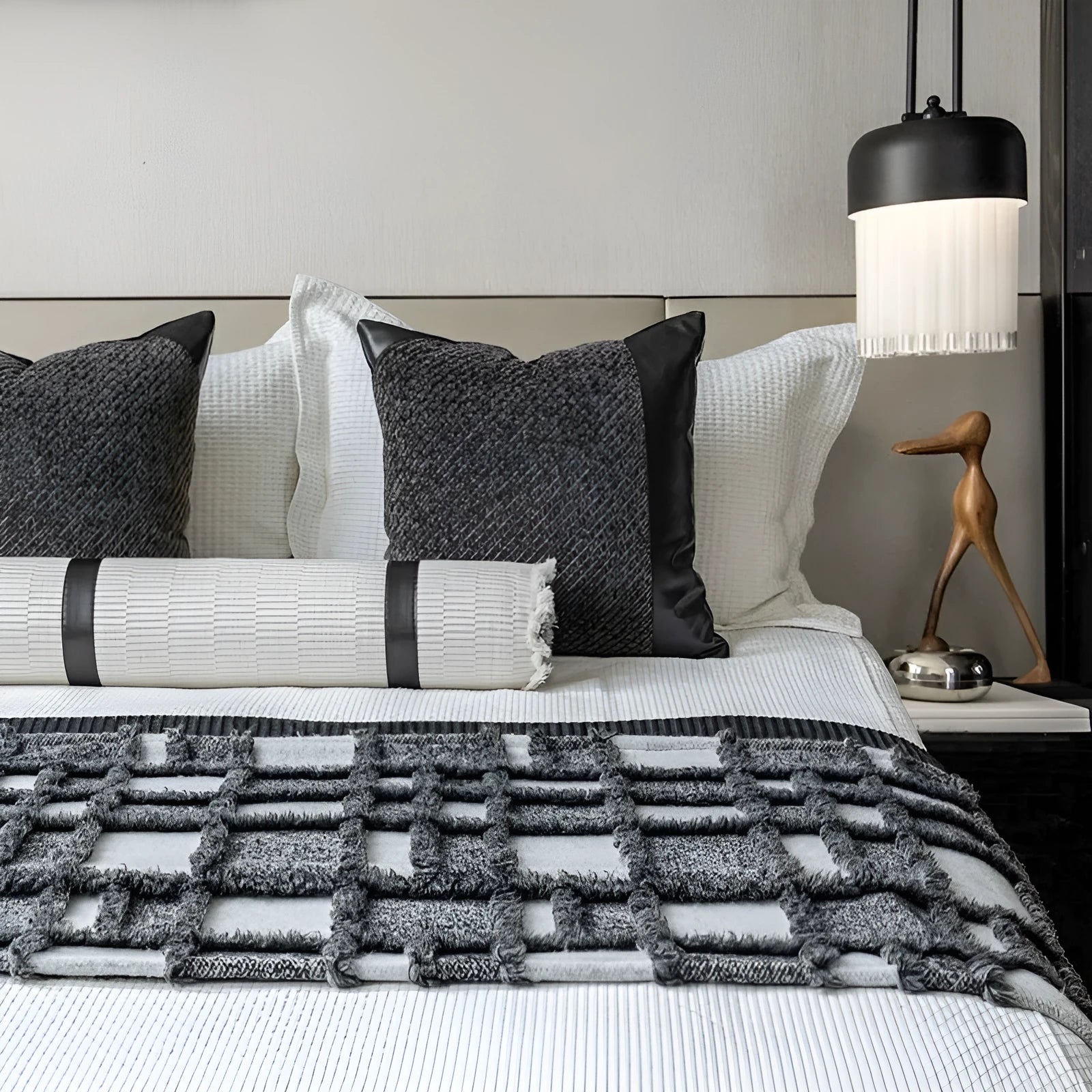 Modern minimalist grey and white plaid bed runner blanket set with matching pillowcase and leather round pillow on a bed.