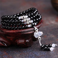 Black agate bracelet with 108 geometric beads on a wrist.