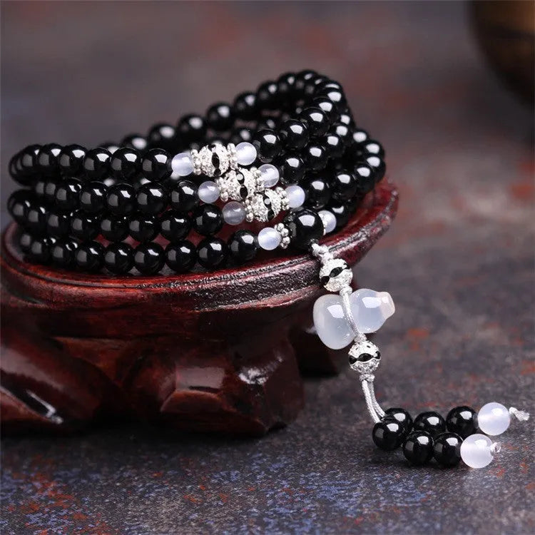 Black agate bracelet with 108 geometric beads on a wrist.