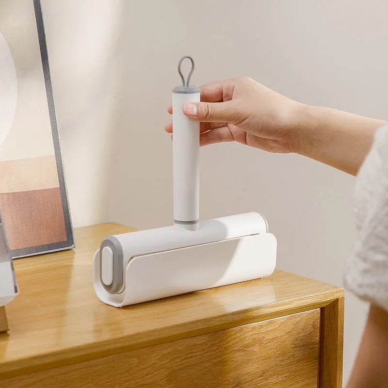 Reusable plastic lint remover roller with a long adhesive paper roll for pet hair and dust on floors.