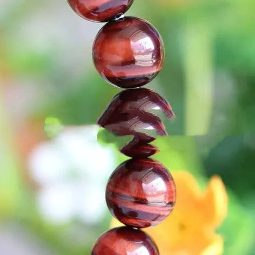 Red tigereye wood alexandrite bracelet with lightning cat's eye pattern on wrist.