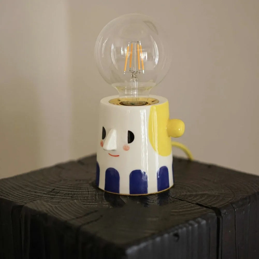 Handmade ceramic bedside lamp with ball headlight colour finish on a table.