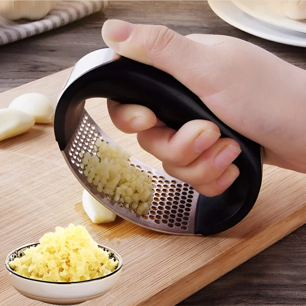 Stainless steel garlic press with ergonomic black handle on a kitchen counter.