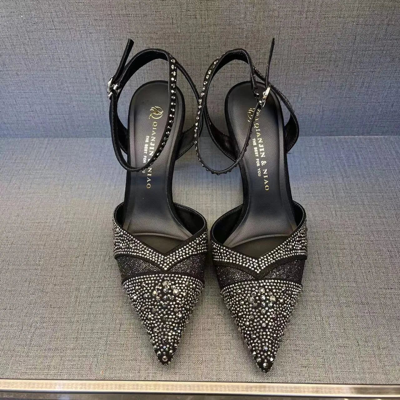 Women's black pointed toe stiletto heels with a hollow design and red sole.