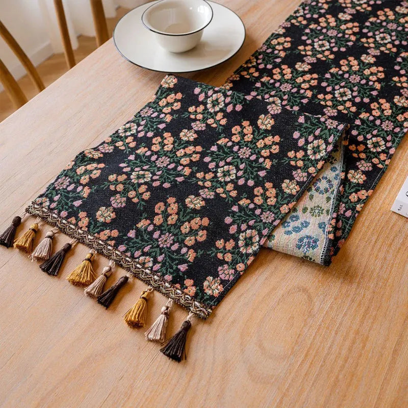 Dark blue striped jacquard table runner with tassel trim laid on a wooden table.