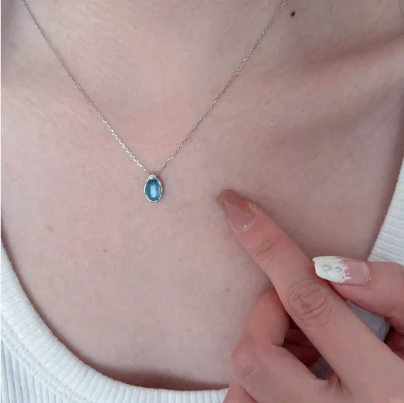 Geometric navy blue water drop pendant on an adjustable copper cross necklace for women.