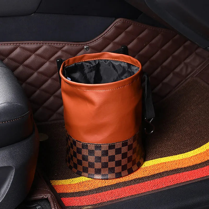 Brown leather folding interior trash can with a retractable handle, shown unfolded.
