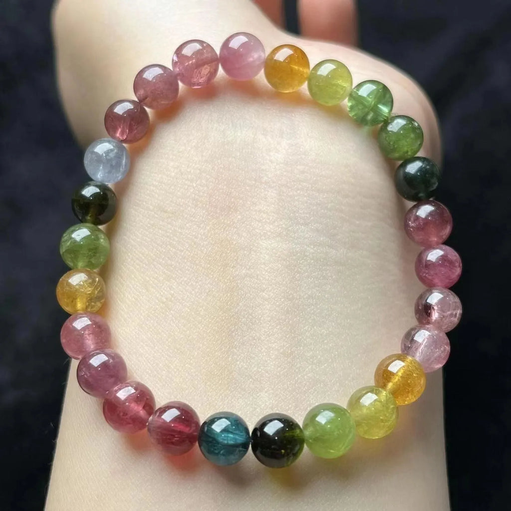 Natural colour tourmaline bracelet with four-leaf clover pearl pendant on wrist.