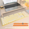 Compact wireless Bluetooth keyboard with mute button and pink backlight on a desk next to a tablet.