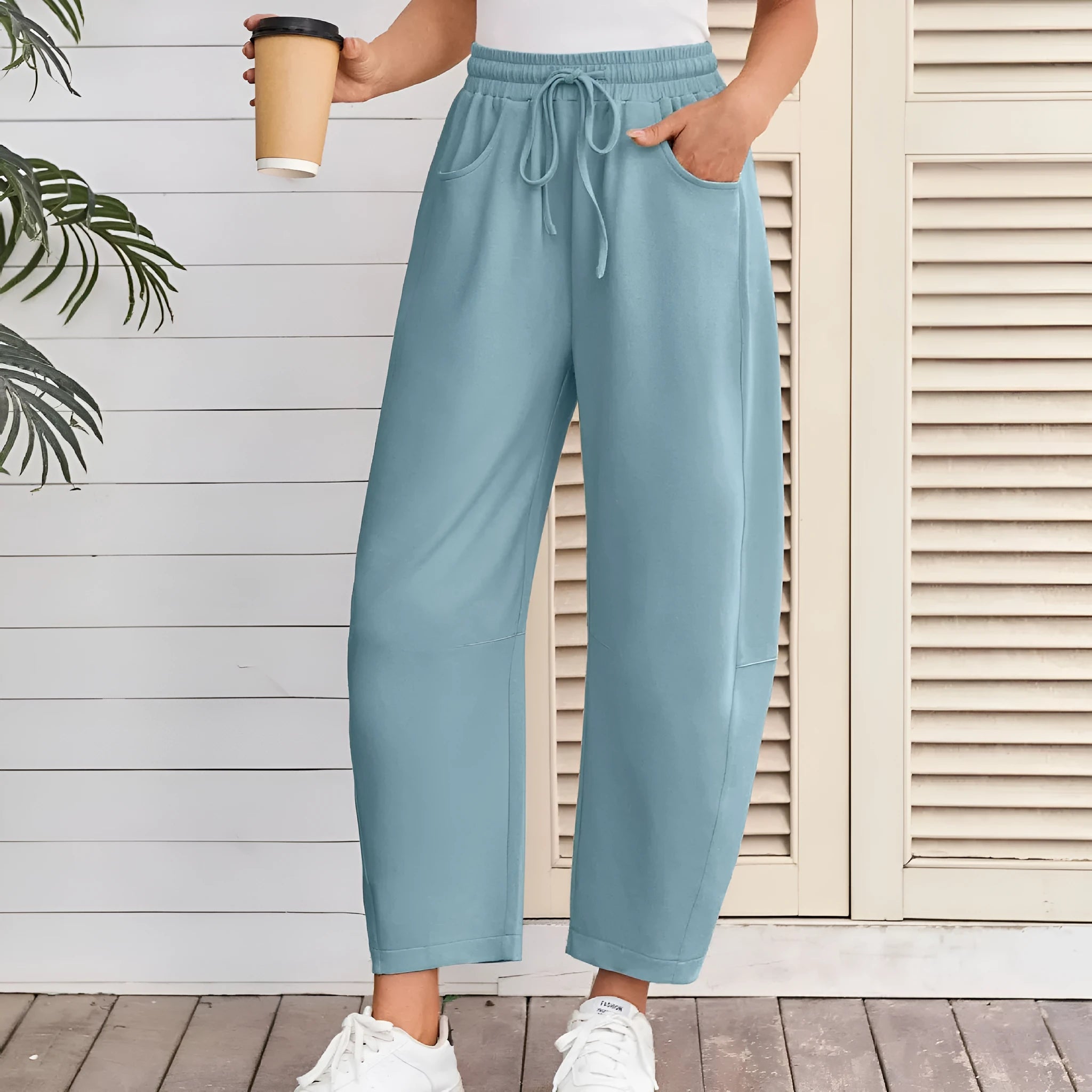 Women's loose cropped sweatpants in apricot colour with drawstring waist and side pockets on a neutral background.