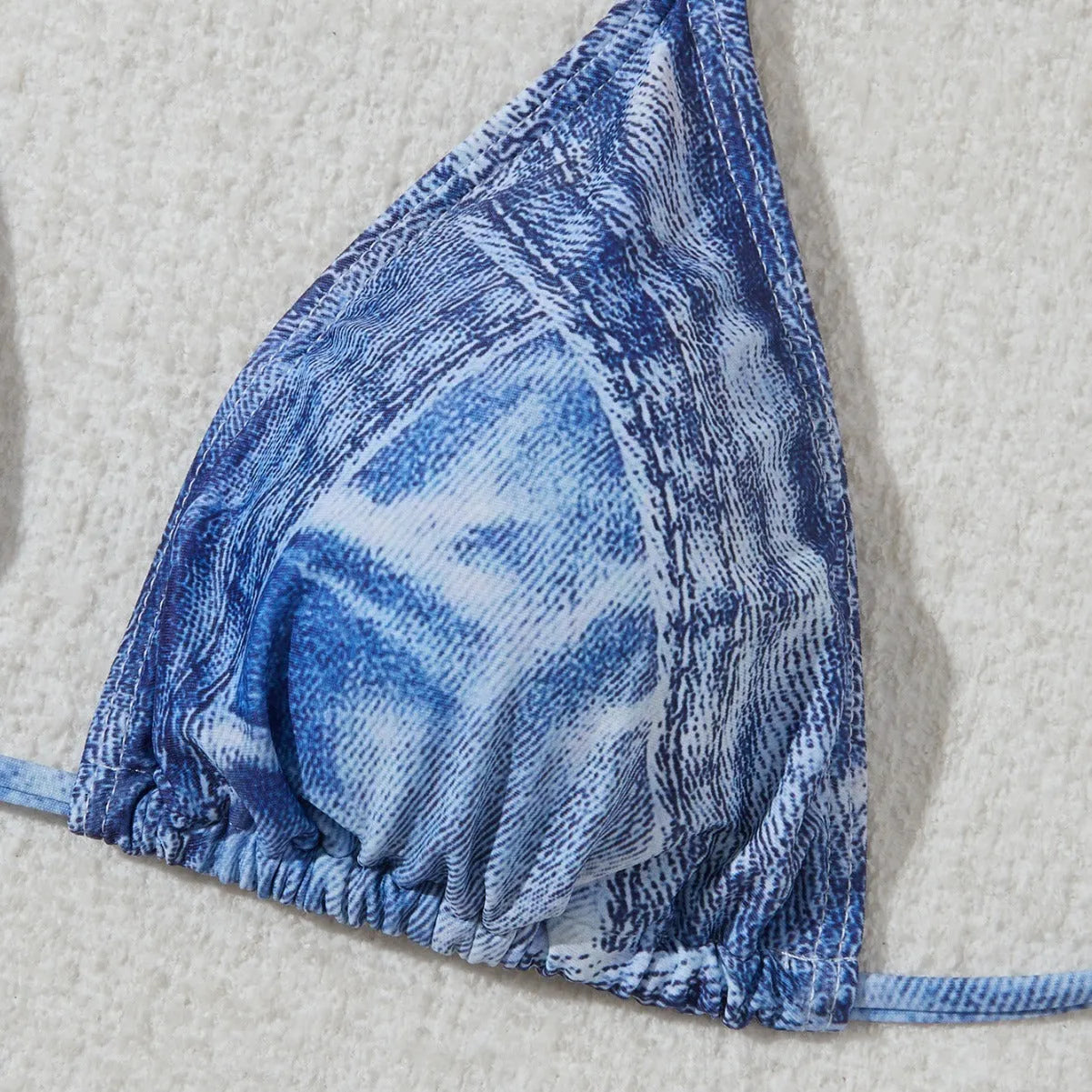 Denim blue printed women's bikini swimsuit with adjustable straps laid flat.