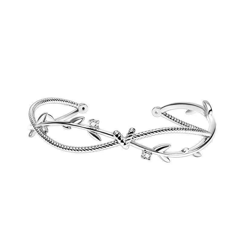 Close-up of a white gold coloured twisted branch sprout design bracelet on a wrist.