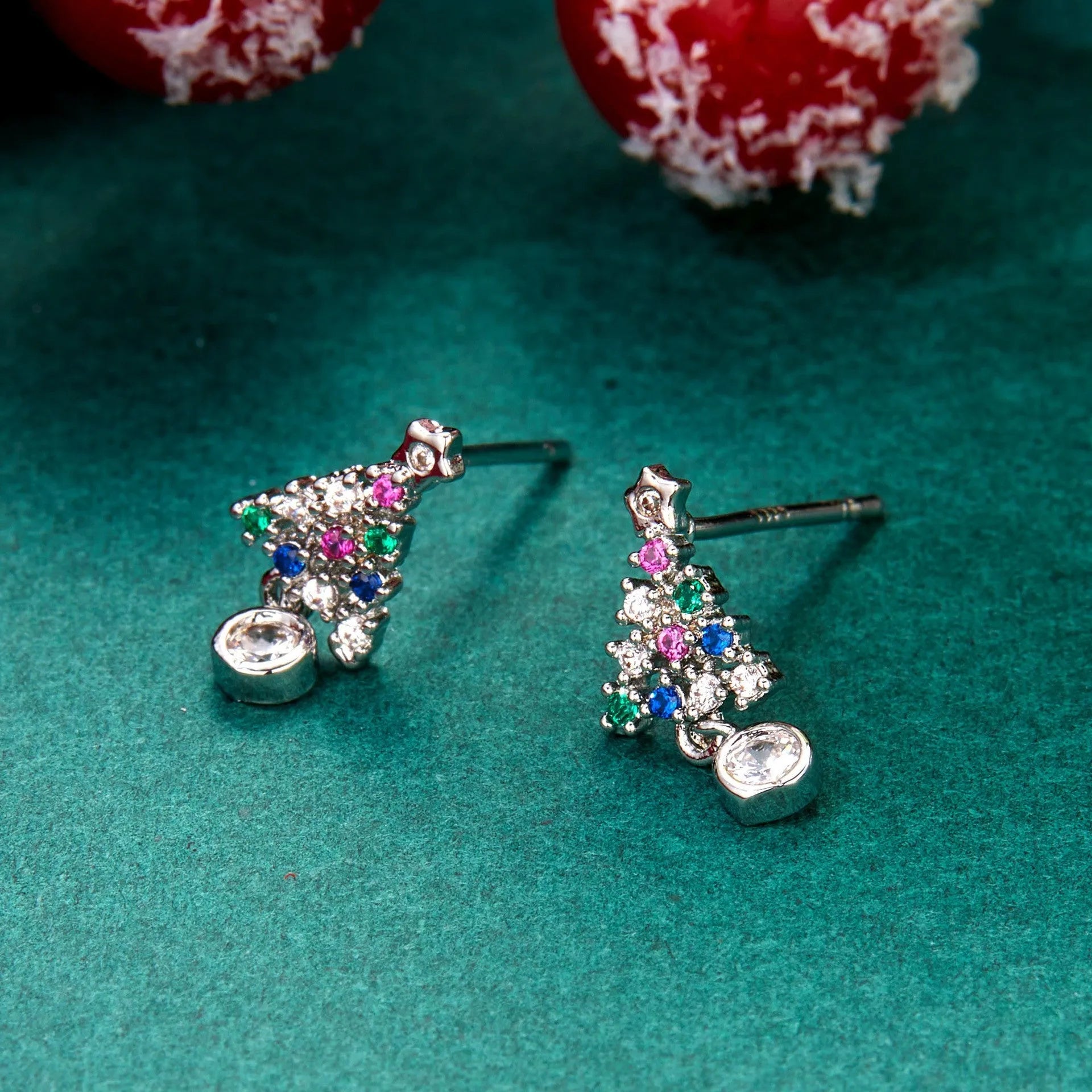 Gold Christmas stud earrings with diamond tree motif and water drop geometric shape on a light surface