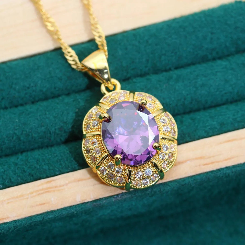 Gold plated necklace, earrings, ring, and bracelet set with blue cubic zirconia stones on a grey background.