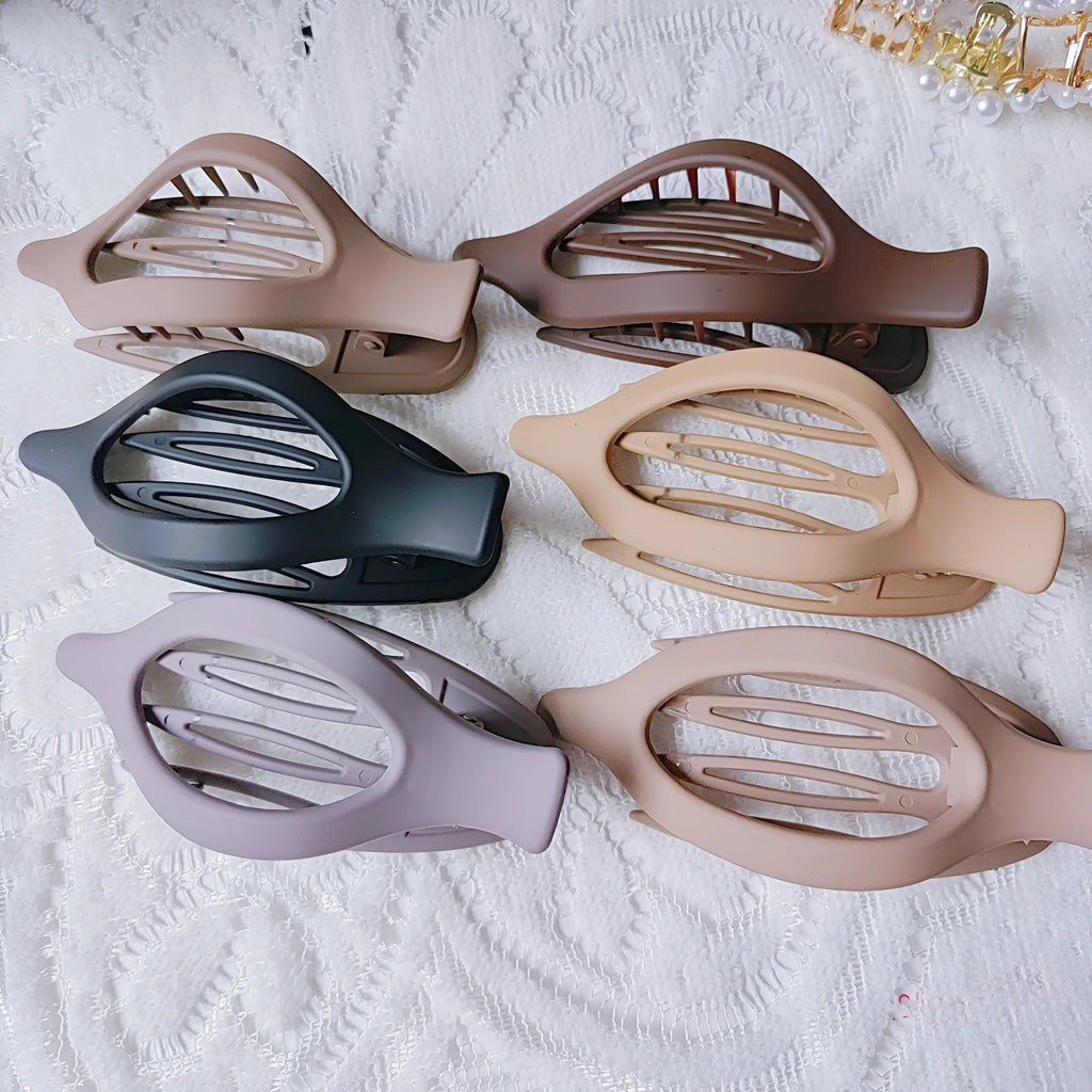 Six nude-coloured plastic hair clips with frosted grip and pointed toe design arranged on white background