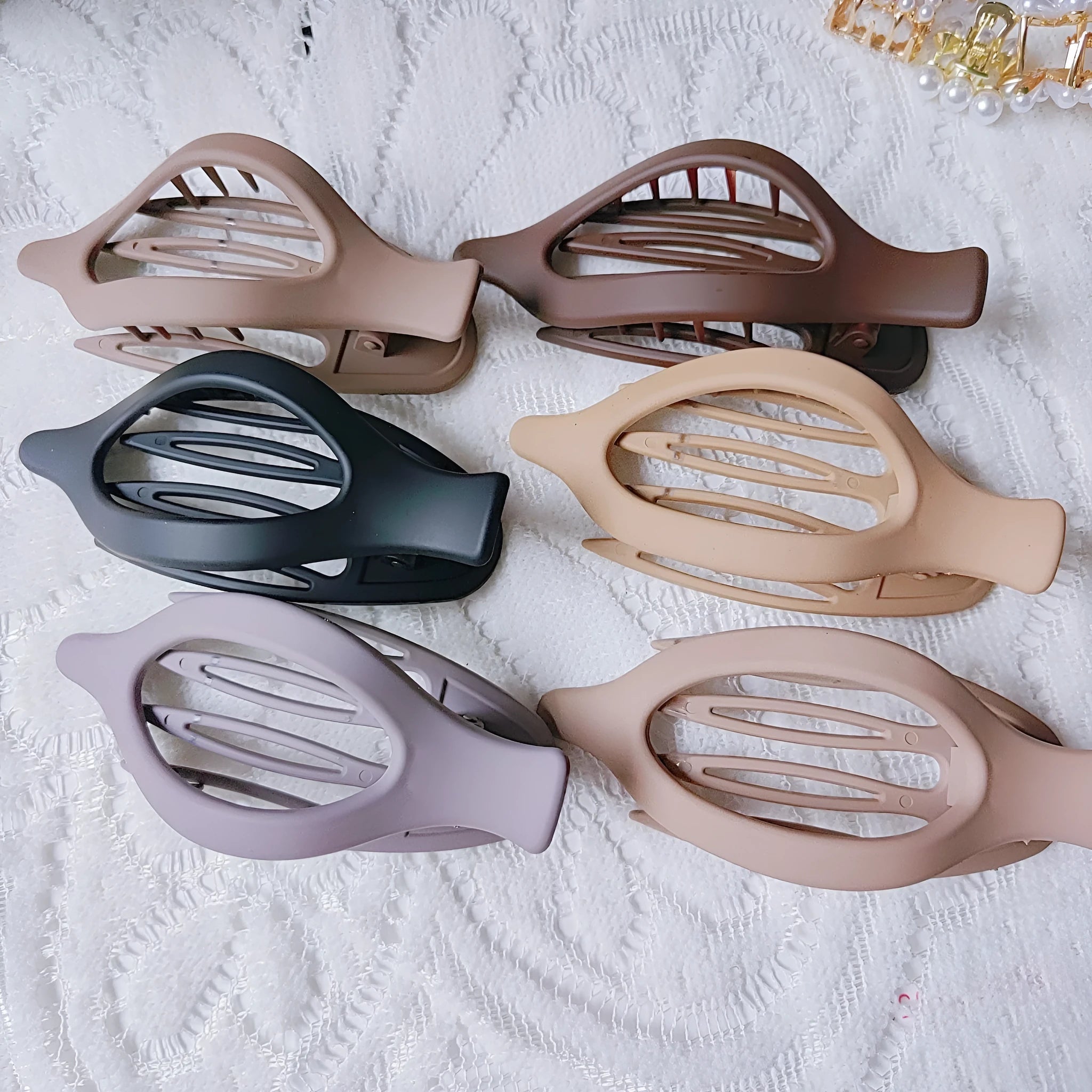 Six nude-coloured plastic hair clips with frosted grip and pointed toe design arranged on white background