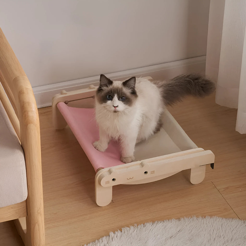 Solid wood cat bed with a removable patterned cover on a wooden floor