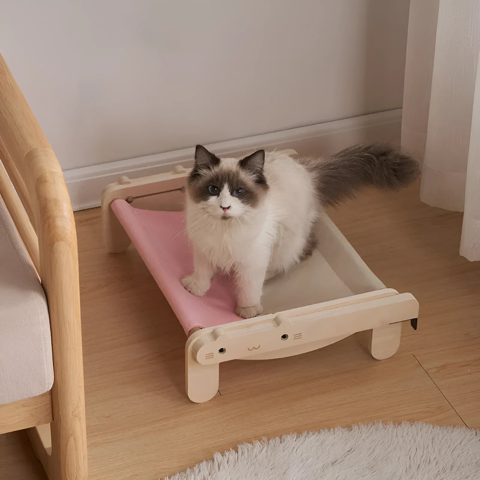 Solid wood cat bed with a removable patterned cover on a wooden floor