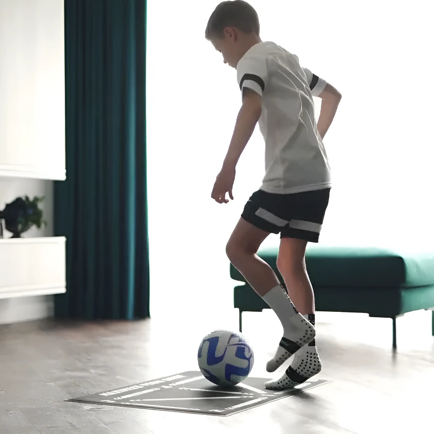 Black rectangular football training mat measuring 60 by 90 cm on a grass surface.
