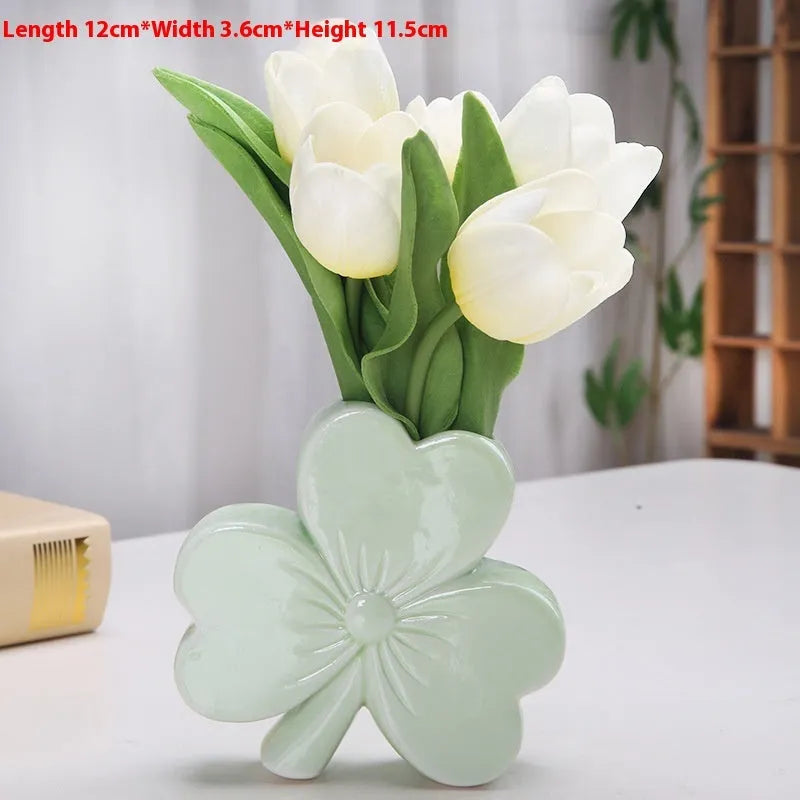 White porcelain clover-shaped ceramic vase on a desk, shown in light green colour.
