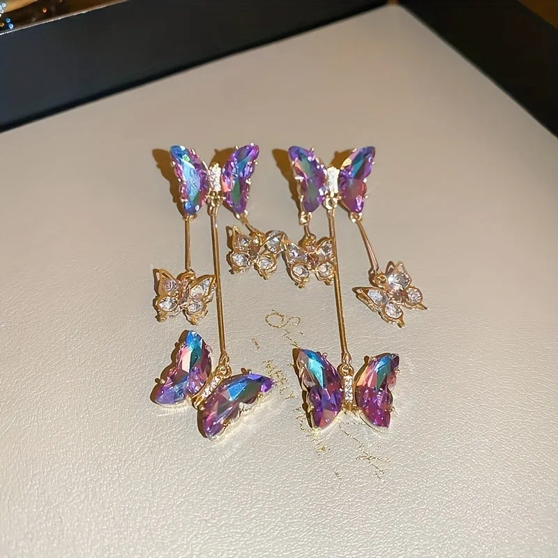 A pair of silver needle crystal flower and butterfly tassel earrings in a blue purple electroplated colour.