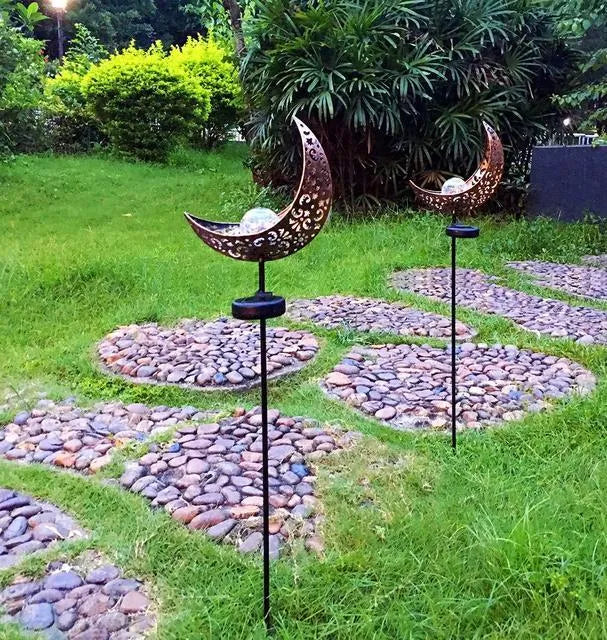 LED solar flame light with warm white glow in a garden, featuring iron and glass construction and stake stand