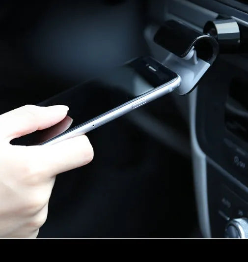 Black universal car phone holder with 360-degree rotating head on a car dashboard