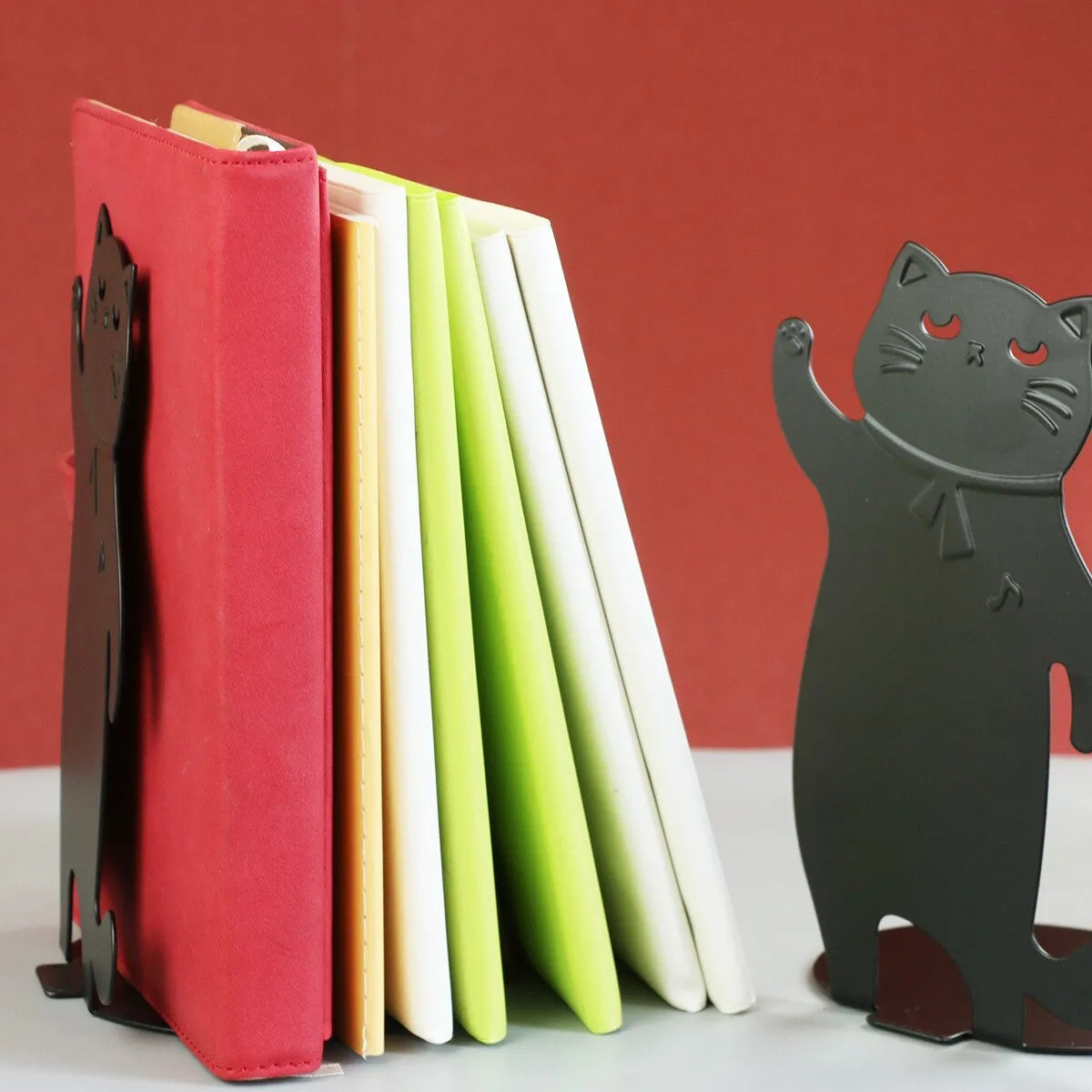 Set of two cartoon cat music themed iron bookends in black and white on a desk holding books upright