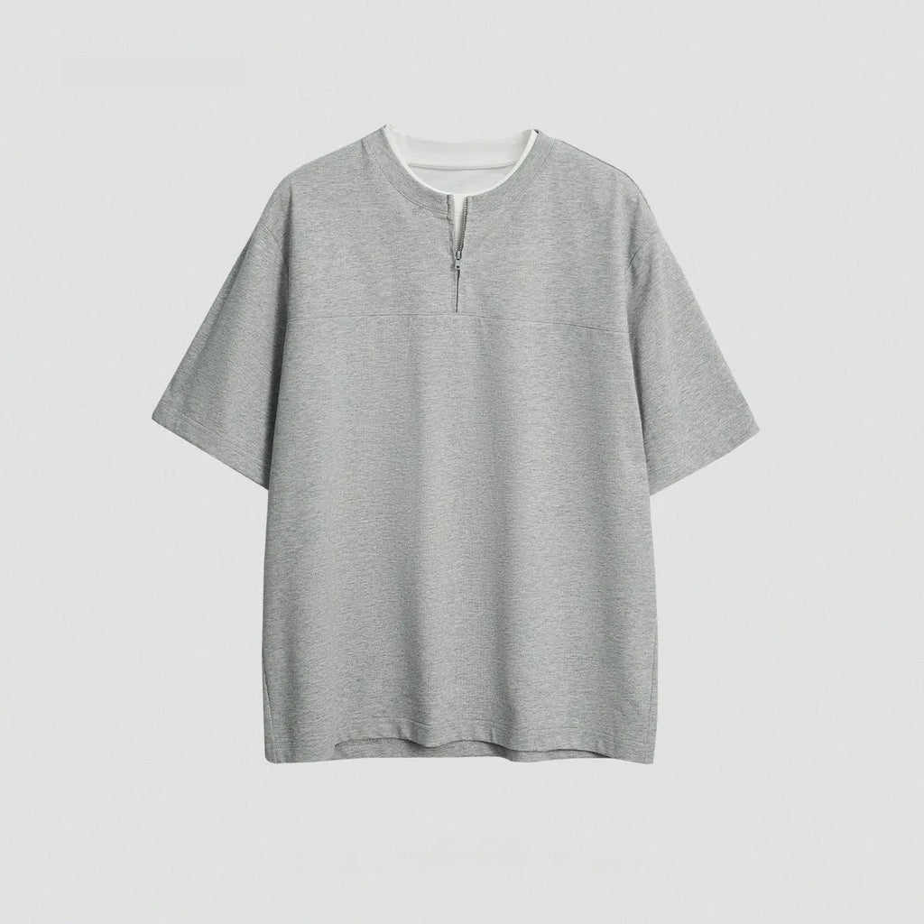 A loose blue cotton blend pullover top with a false zip and patchwork collage stitching detail.