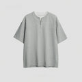 A loose blue cotton blend pullover top with a false zip and patchwork collage stitching detail.
