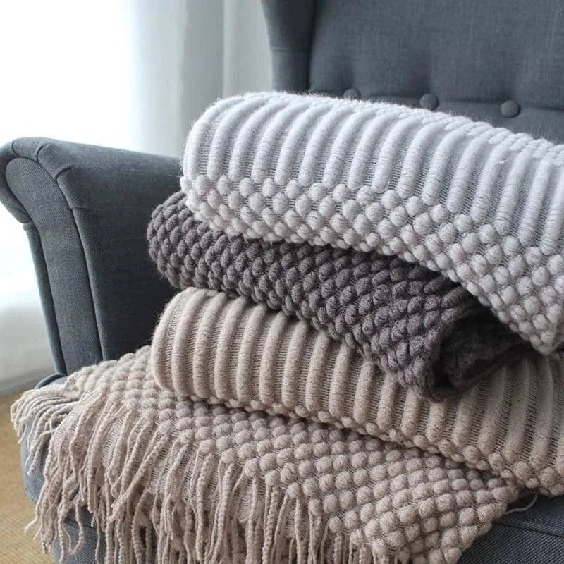 Small grey polyester nap blanket folded on a sofa, showing its 127x170cm size.